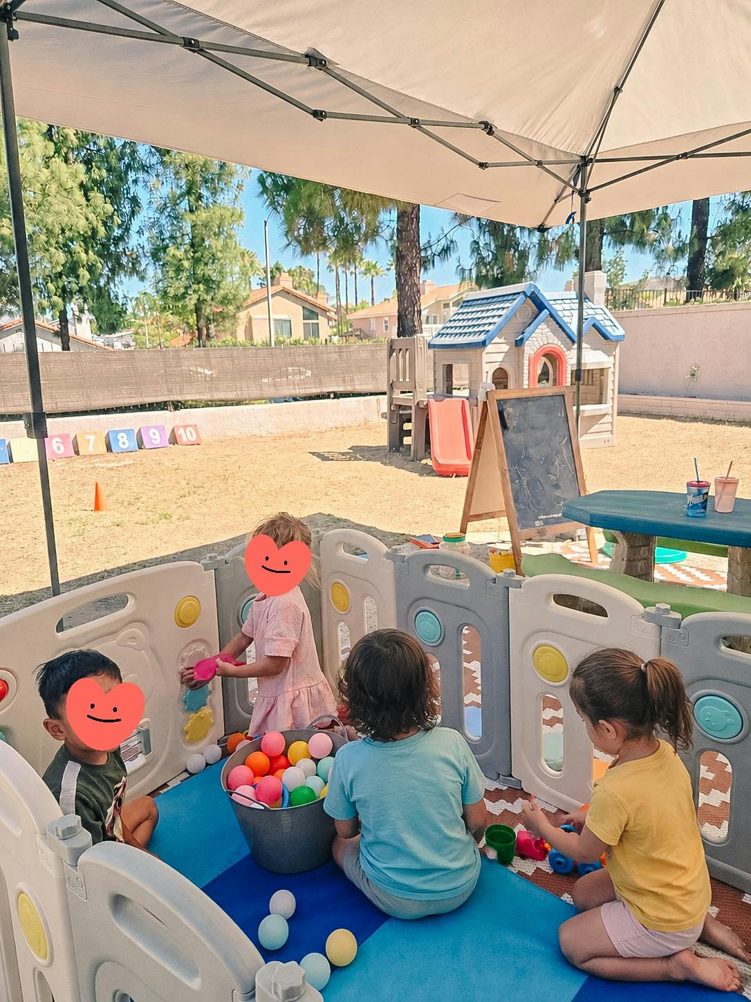 Children playing with a ball pit in a playpen under a canopy