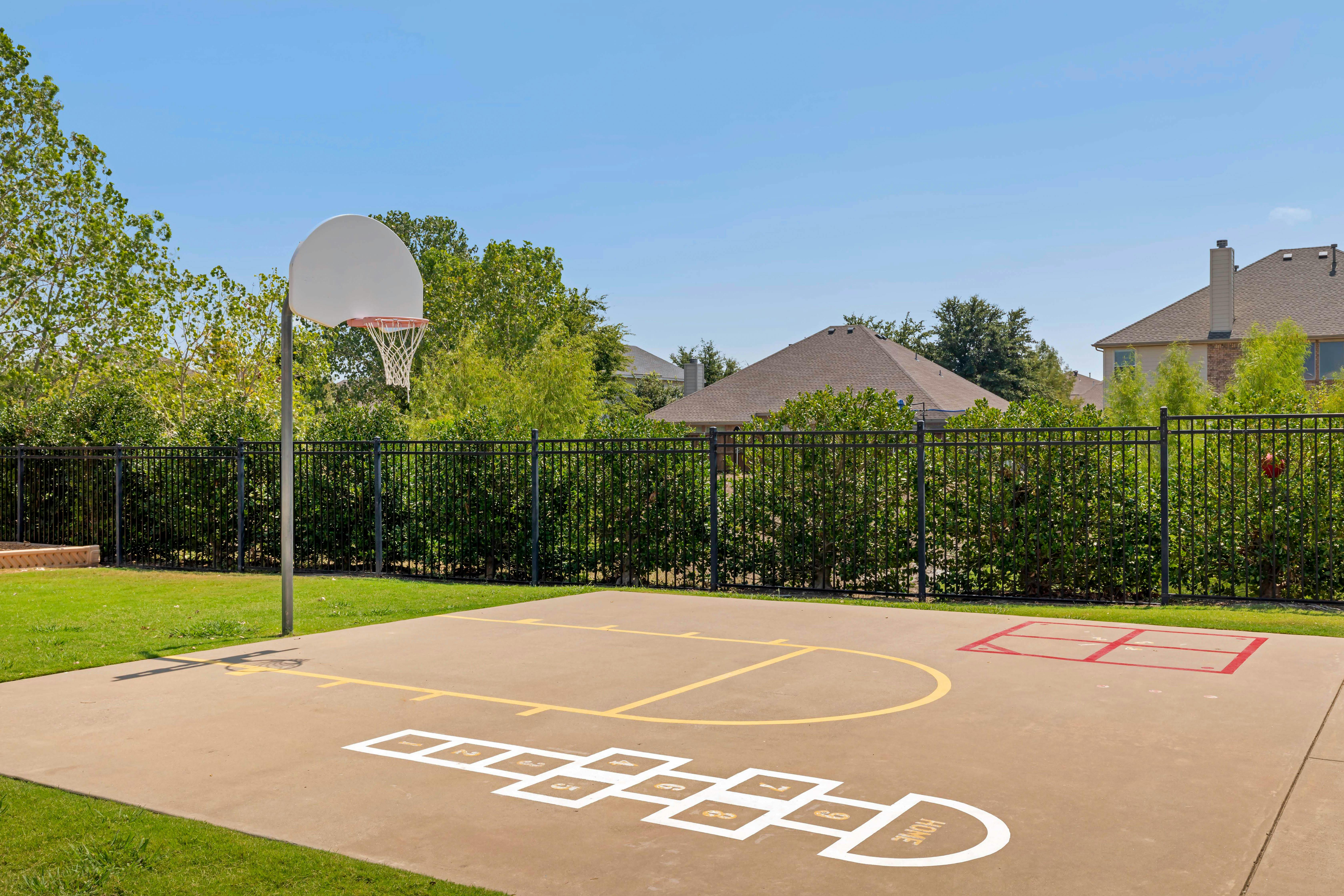 Outdoor concrete court with basketball hoop and hopscotch lines