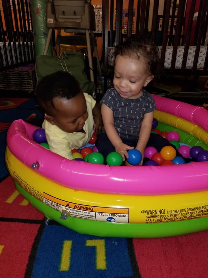Two children playing in a colorful inflatable ball pit
