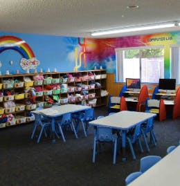 Classroom with small tables and chairs, shelves, and computers