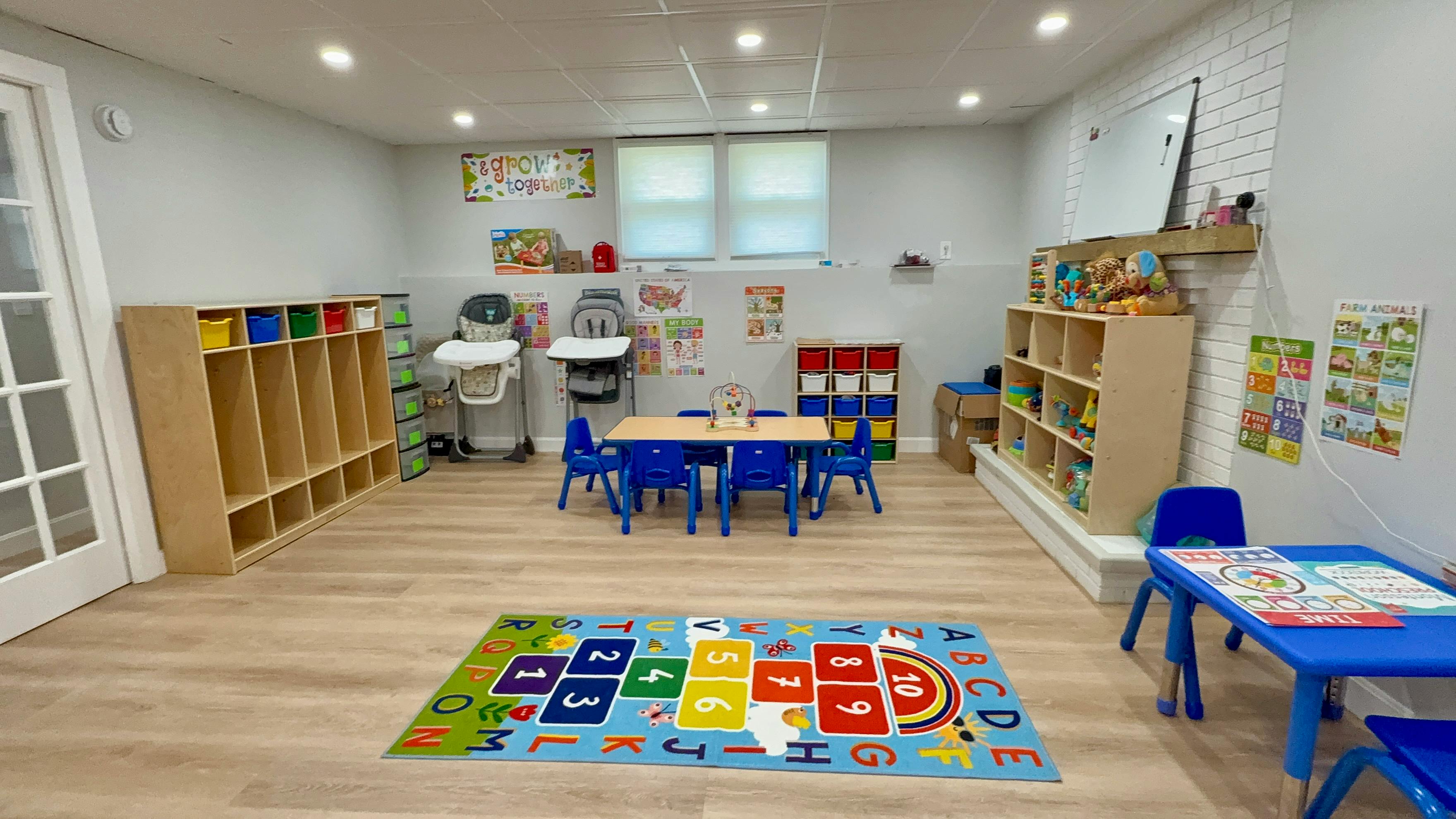 Playroom with small tables and chairs, storage cubbies, and a colorful rug
