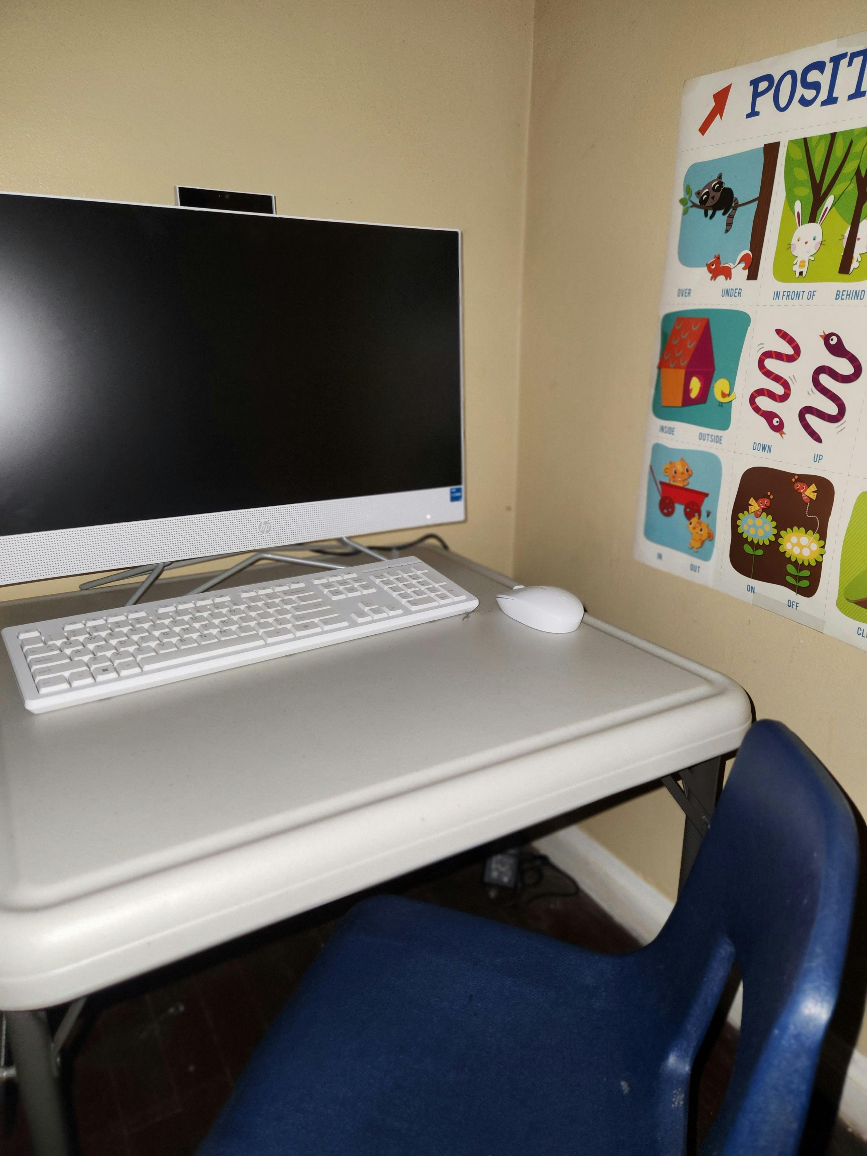 Computer monitor, keyboard, and mouse on a desk with a blue chair