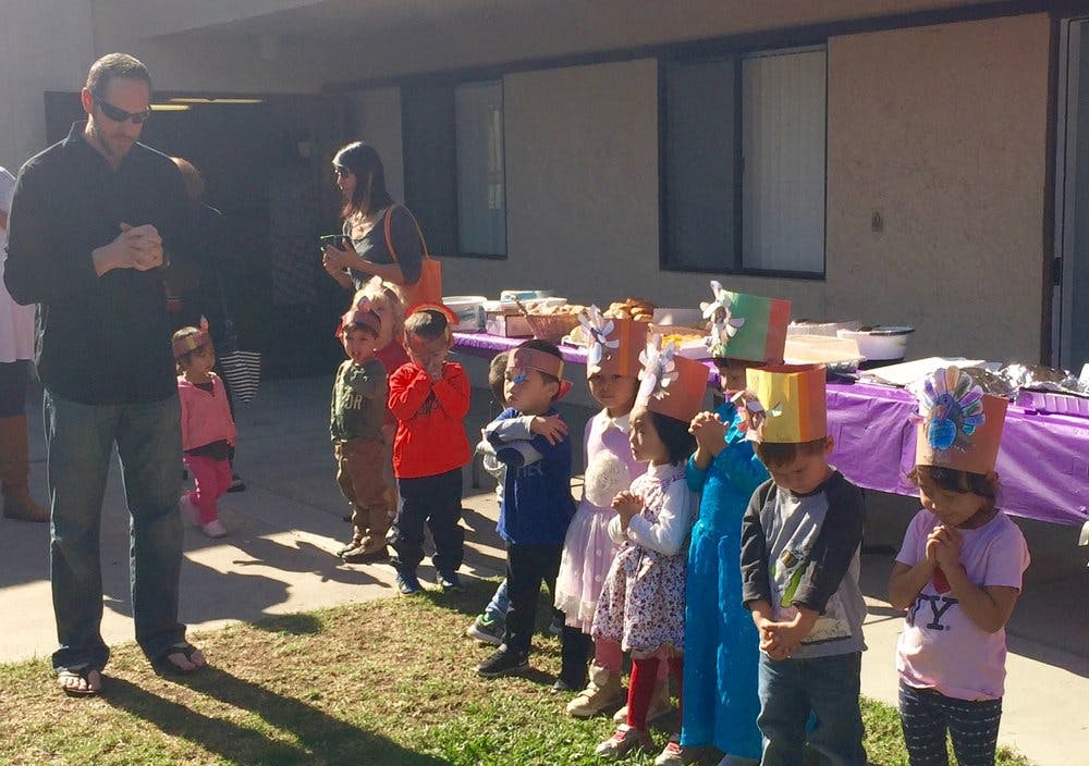 Adults and children in paper crowns standing in a line outdoors