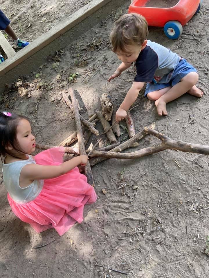 Two children playing with sticks on the ground