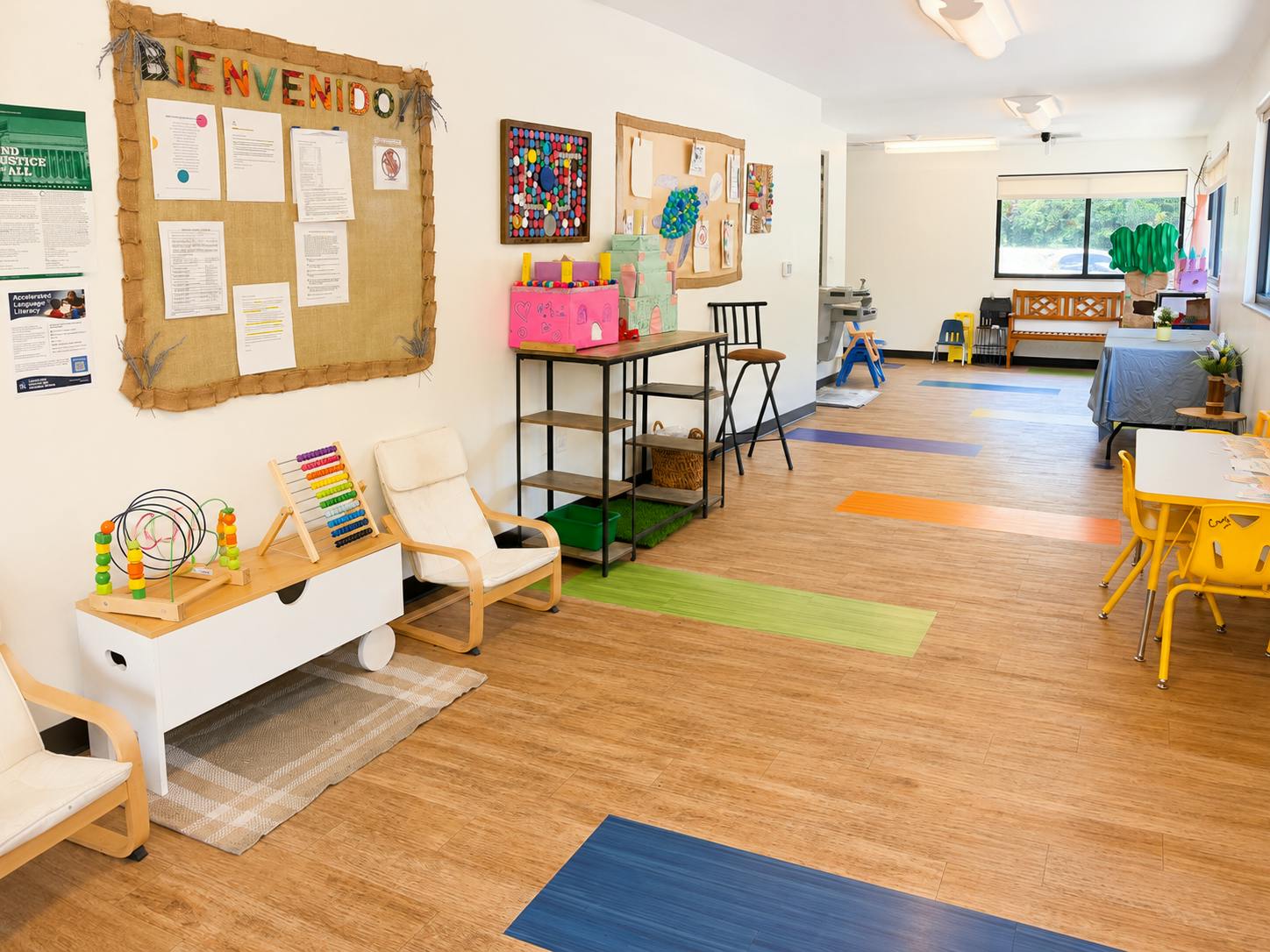 Classroom interior with furniture, play equipment, and a Bienvenidos bulletin board