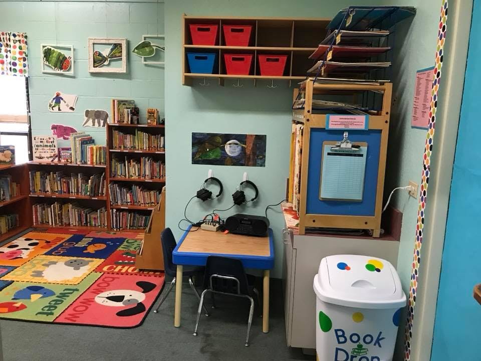 Children's library area with colorful rug, bookshelves, and small table with headphones