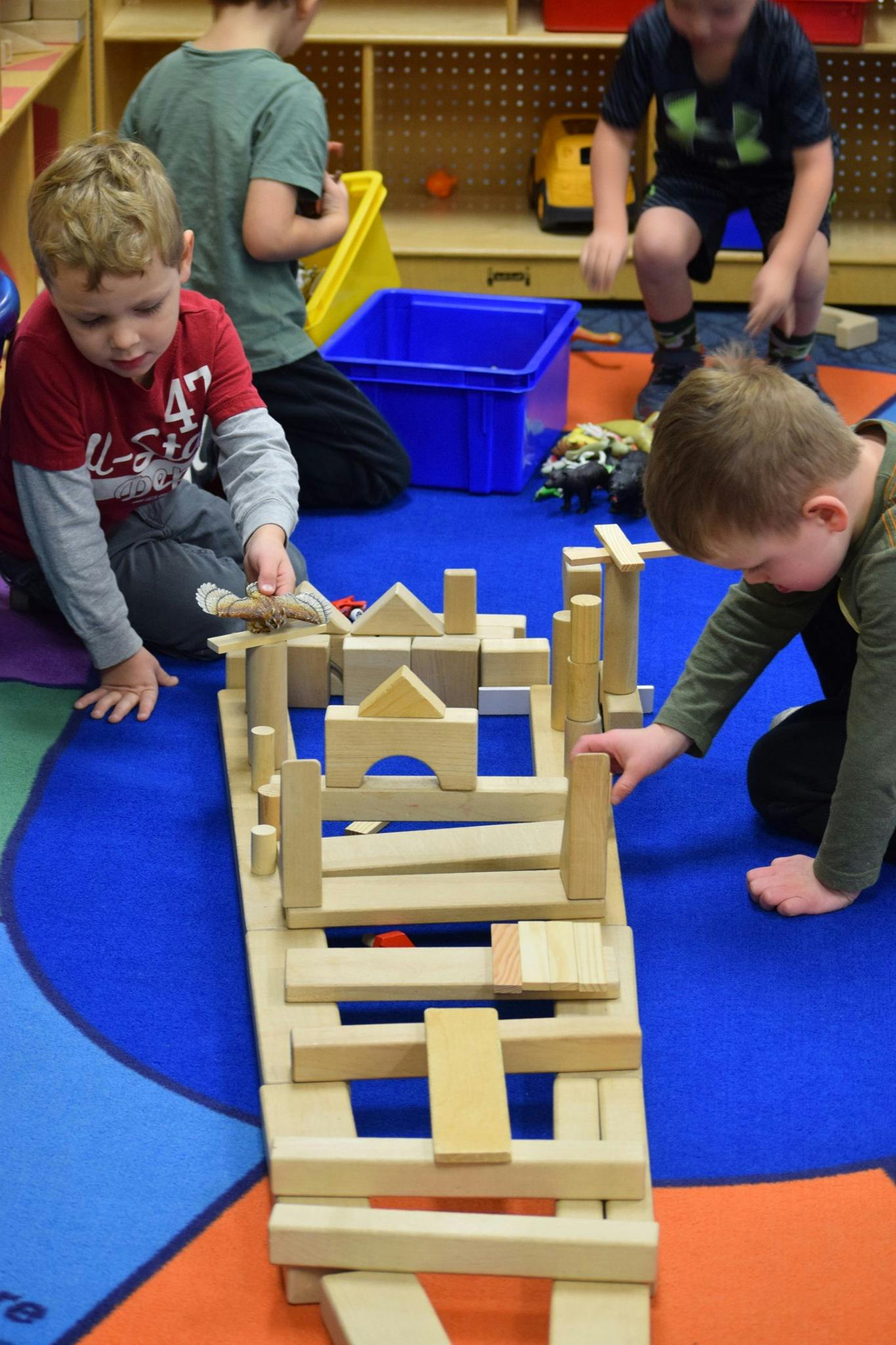 Children playing with wooden blocks on a colorful rug
