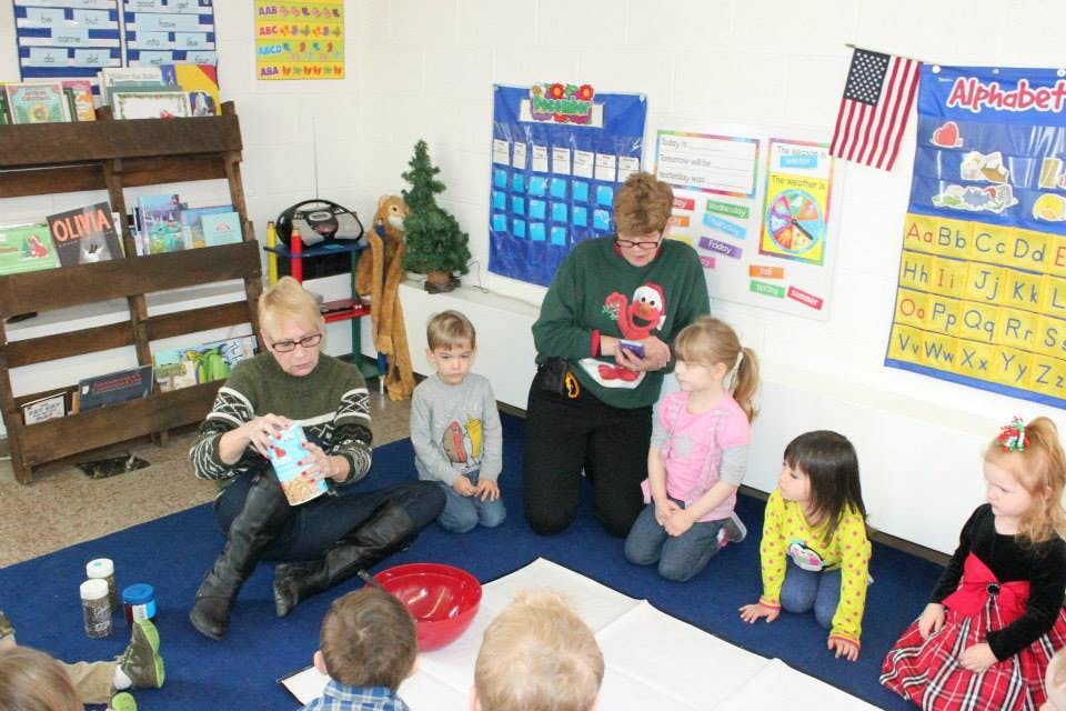 Adults and children sitting on the floor in a classroom