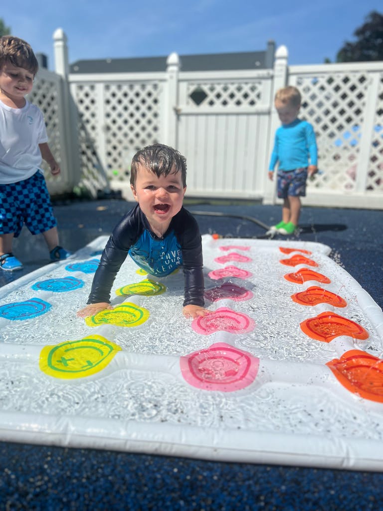 Child crawling on a water play mat with colorful shapes