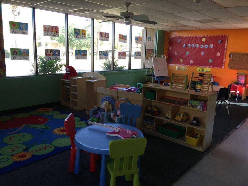 Classroom with small tables and chairs, shelves with toys, and large windows