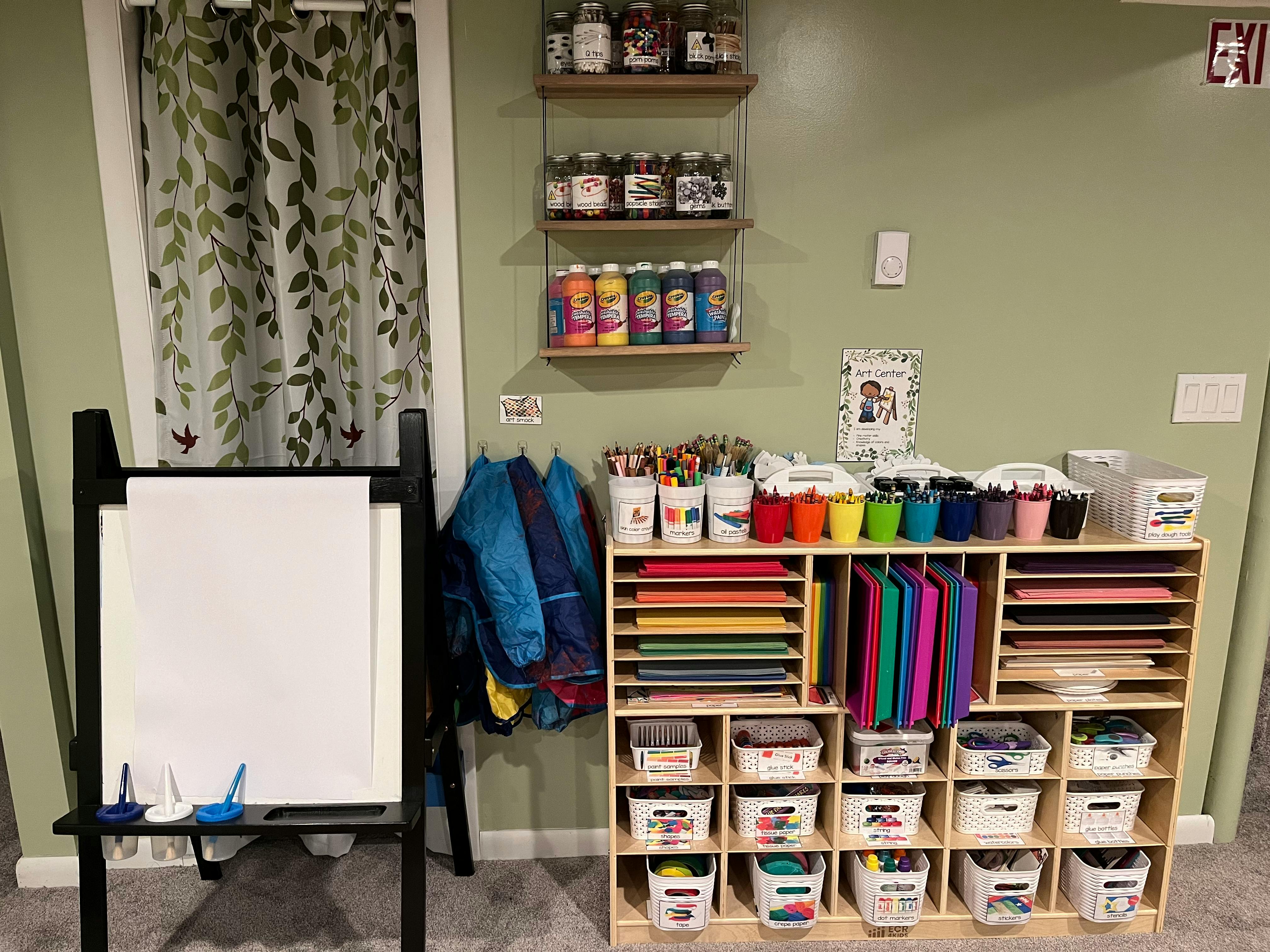 Art supplies organized on shelves and in bins next to an easel