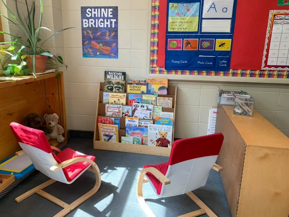 Classroom reading nook with two red chairs and a bookshelf