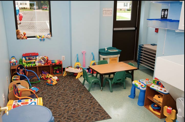 Playroom with small table and chairs, toys on shelves and floor