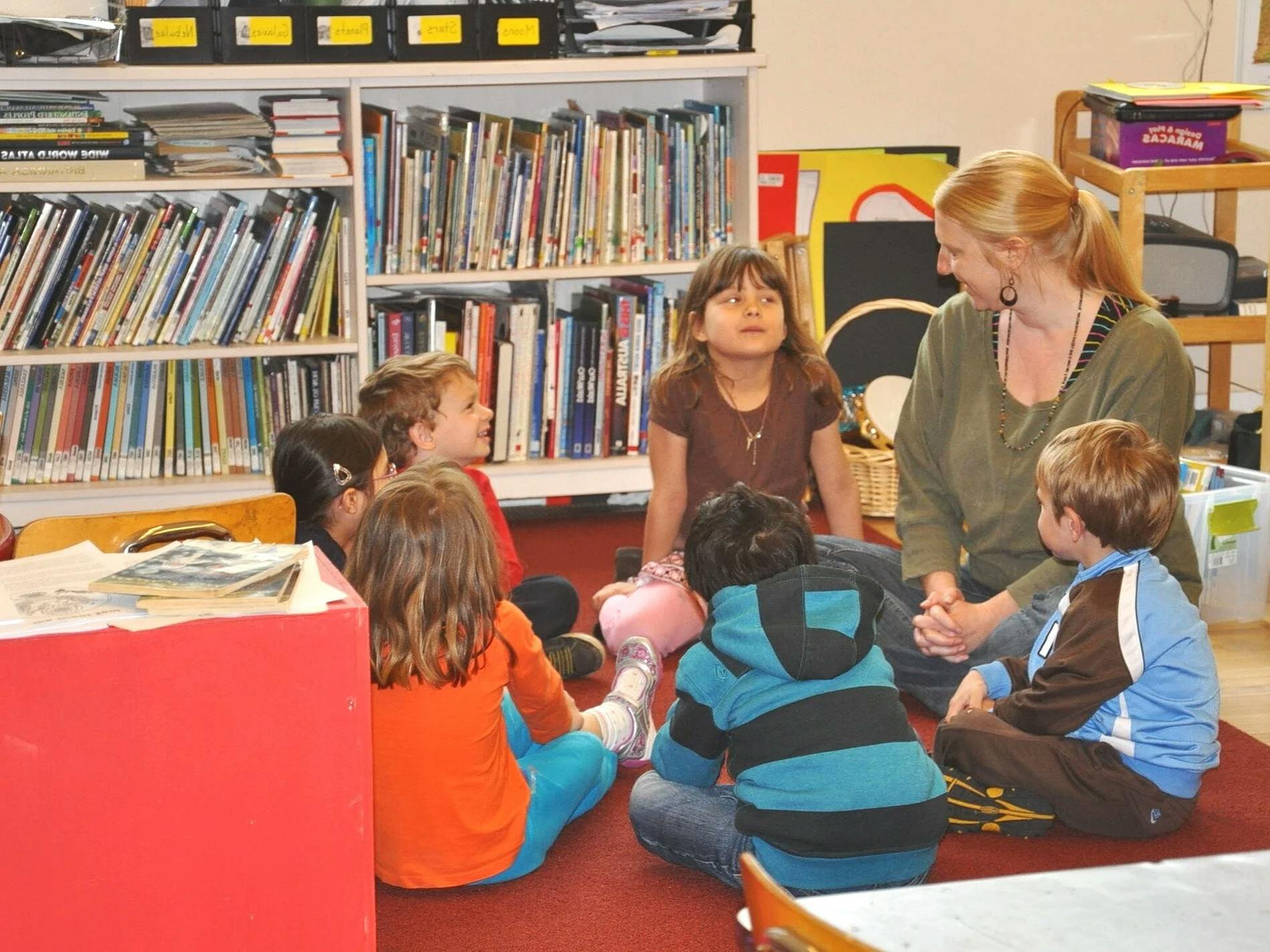 Adult and several children sitting on a rug in a classroom