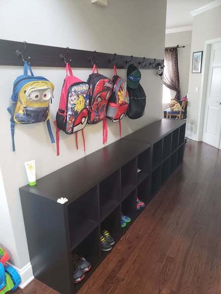 Backpacks hanging on hooks above a shoe storage bench