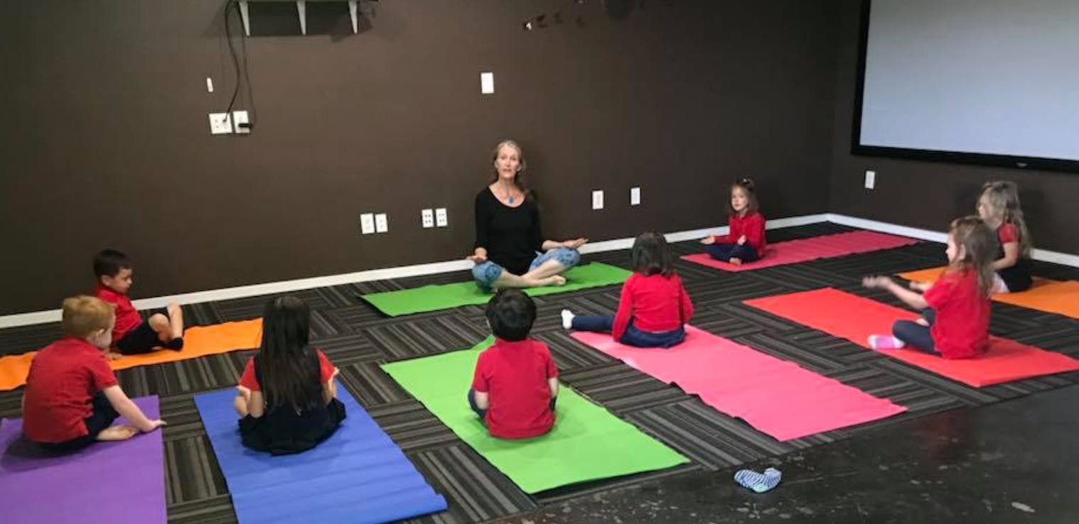 Adult and children sitting on yoga mats