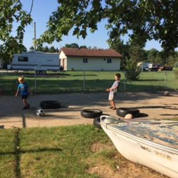 Two children playing with a soccer ball and tires outdoors