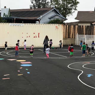 Adult and children playing on a painted outdoor court