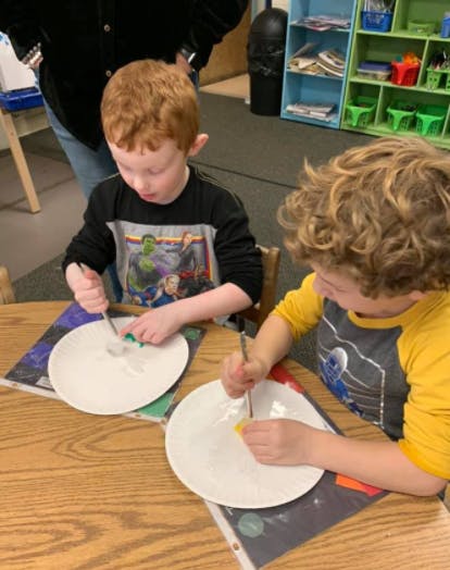 Two children painting on plates at a table