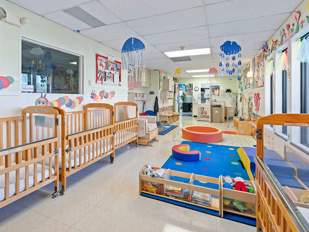 A colorful childcare room with cribs and play areas