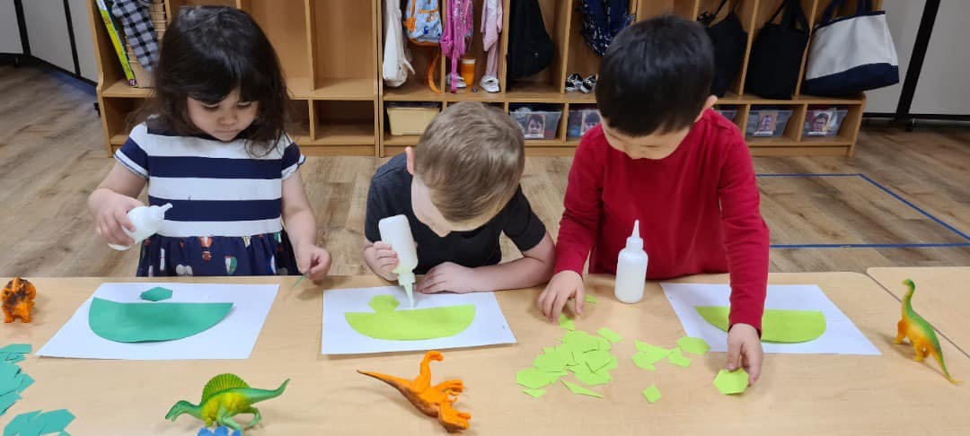 Three children doing crafts with glue and paper