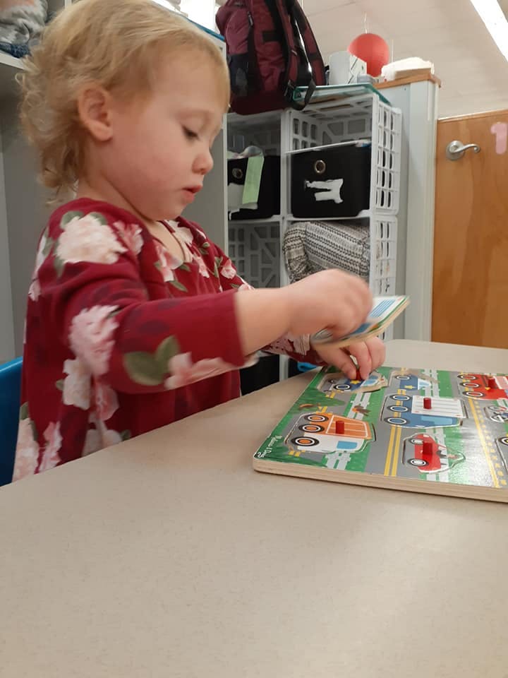 Child playing with a vehicle puzzle on a table