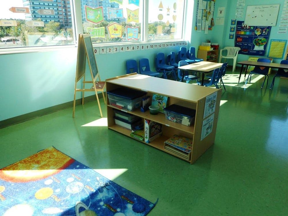 Classroom with a bookshelf, tables, chairs, and a window