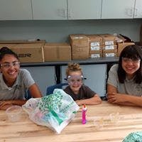 Three people wearing safety glasses at a table