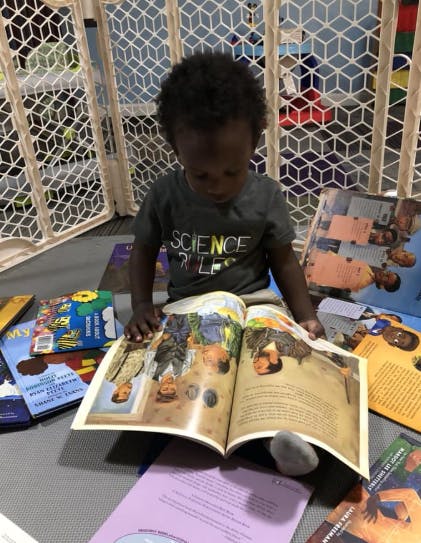 Child sitting on floor looking at an open book