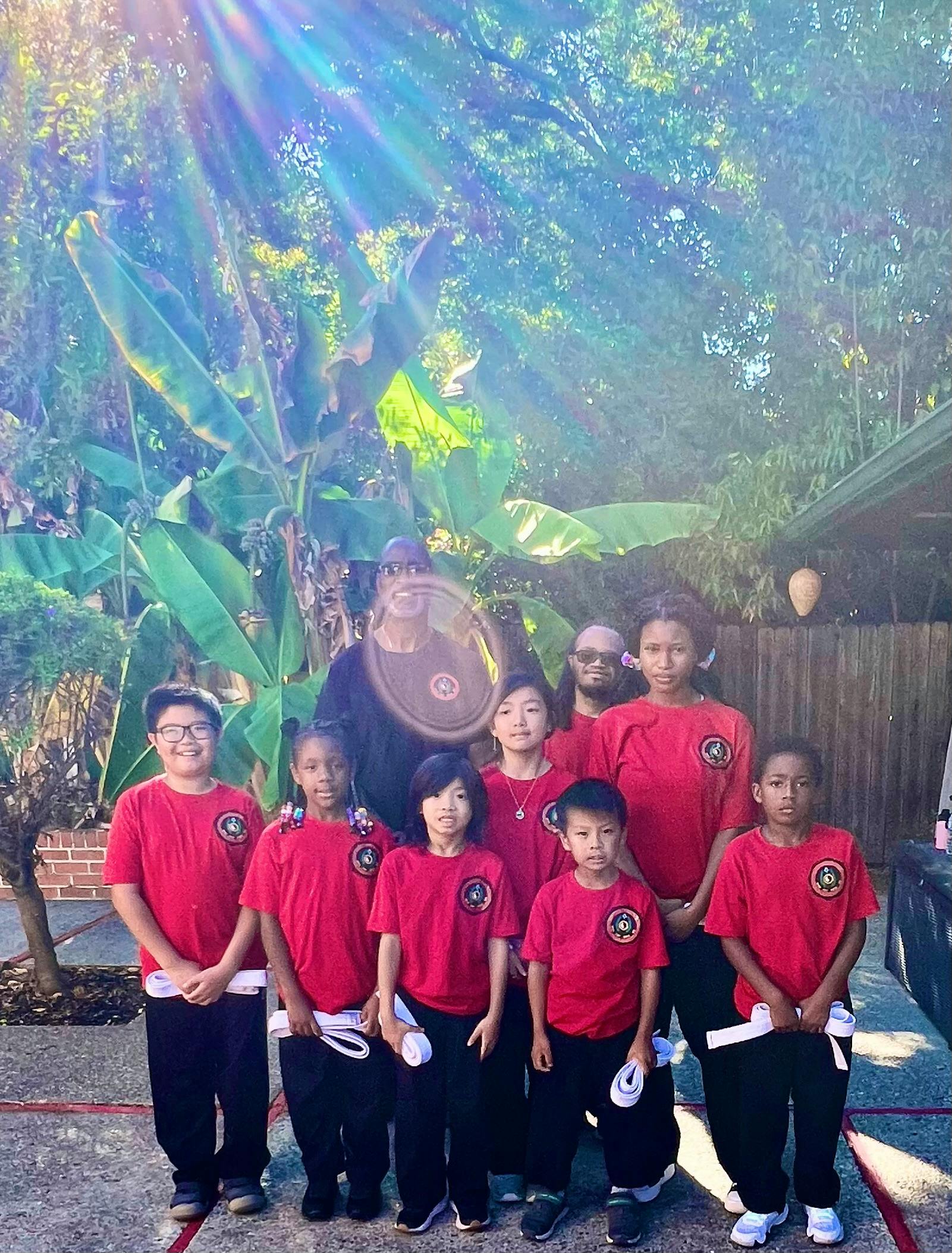 Group of adults and children in red shirts holding white belts