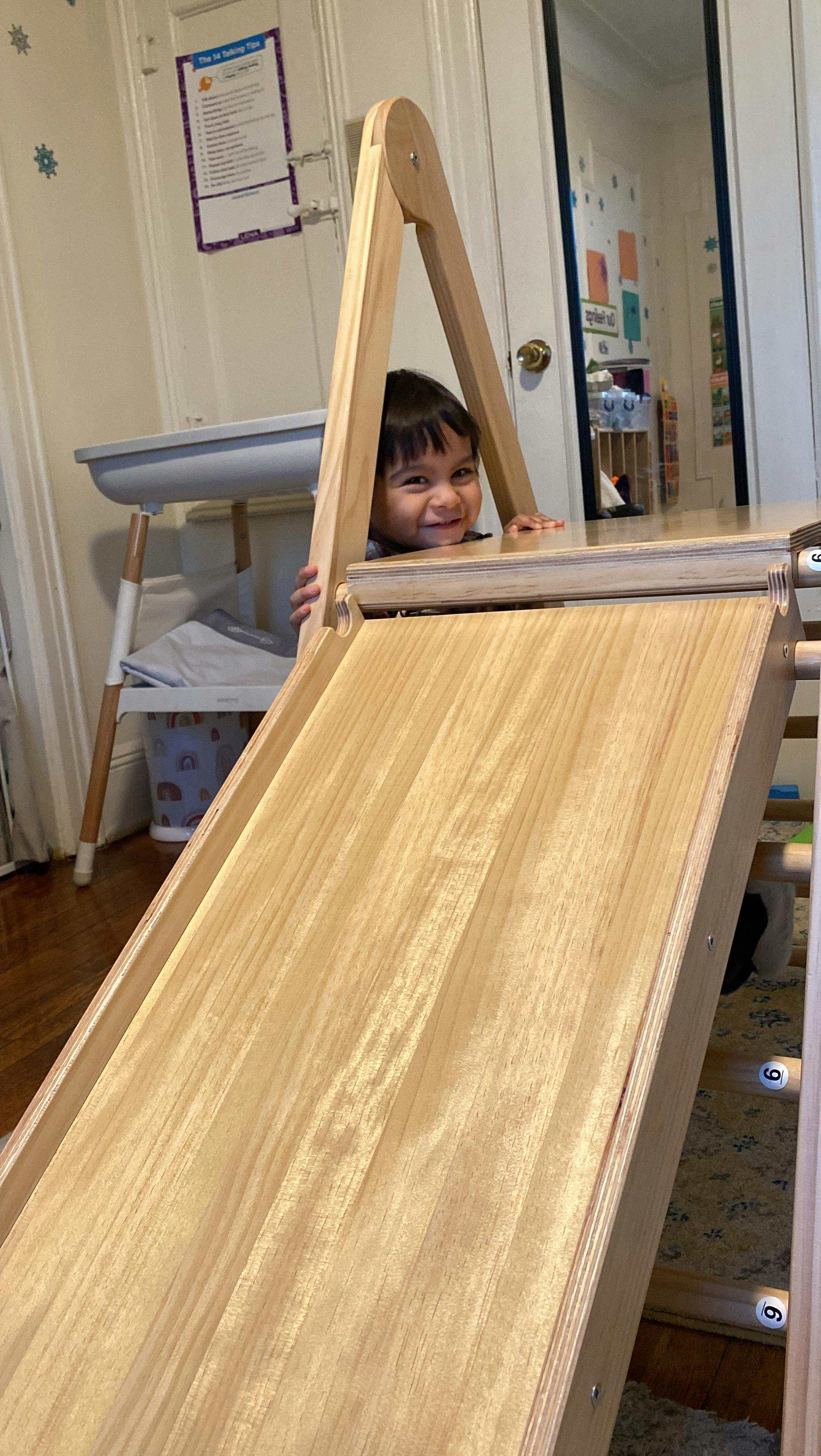 Child peeking over a wooden play structure