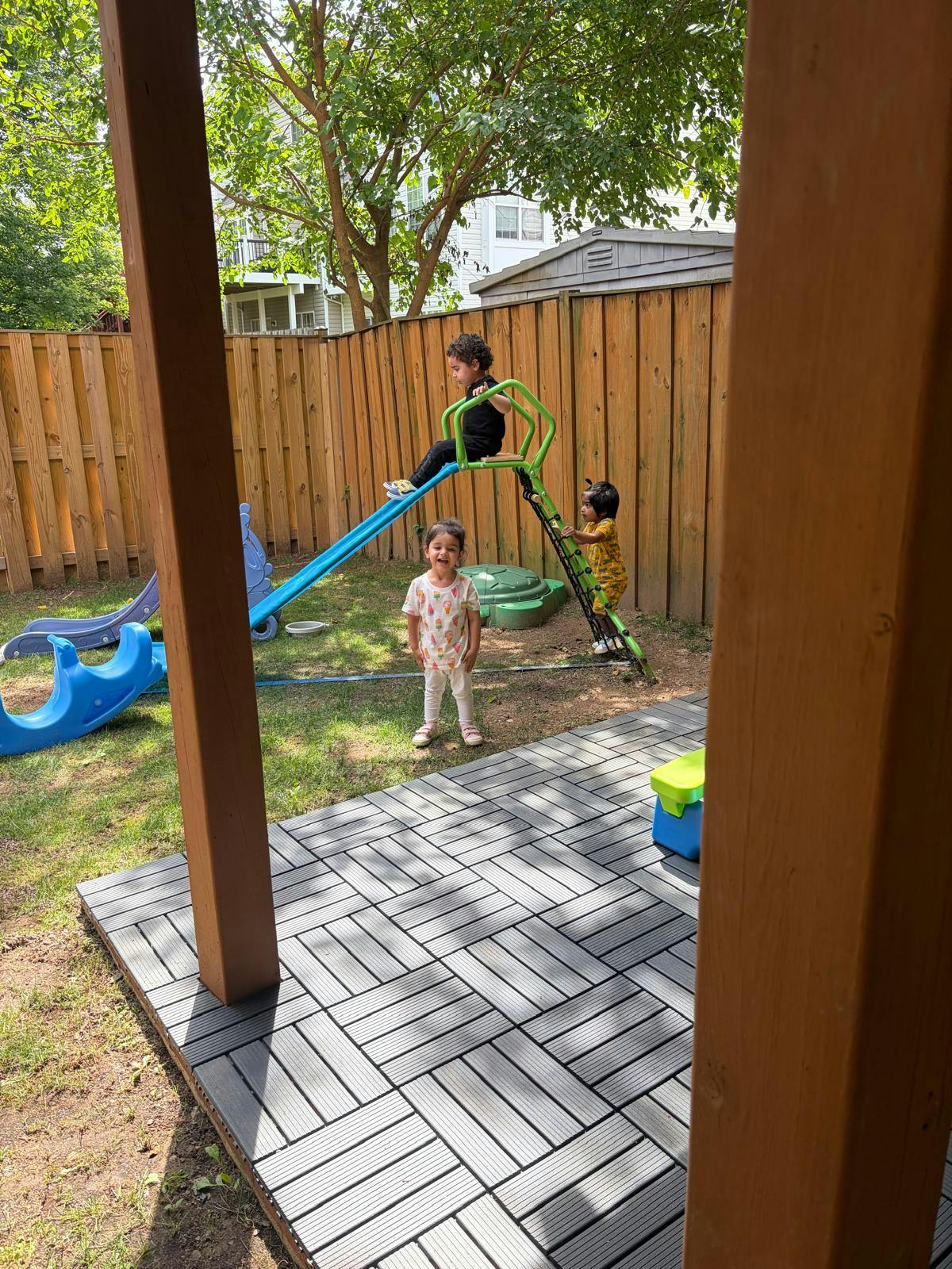 Three children playing on backyard playground equipment