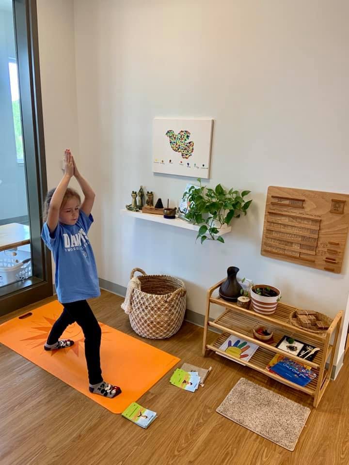 Child on a yoga mat with hands raised in a yoga pose