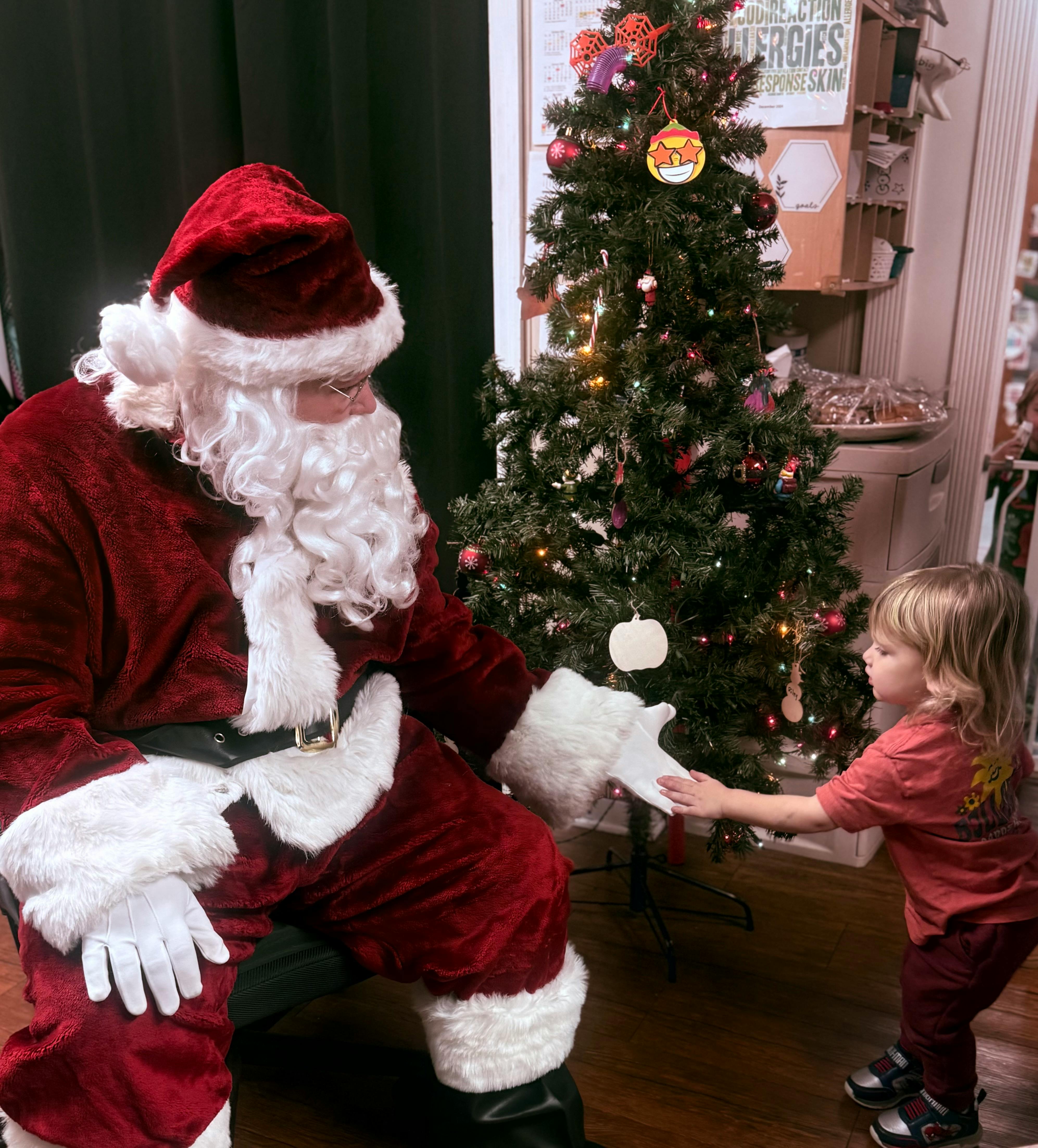 Person dressed as Santa Claus kneeling and reaching out to a child