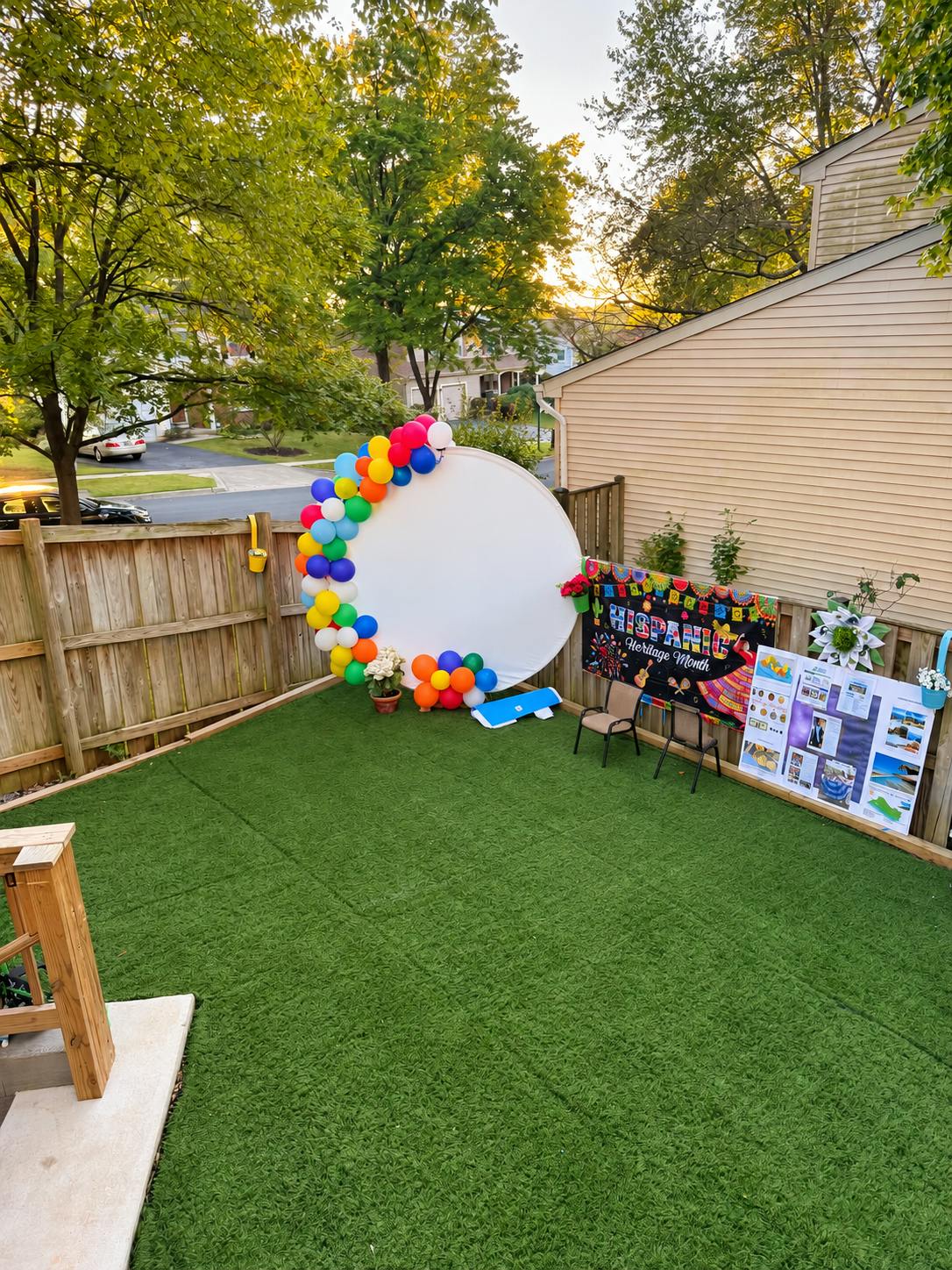Backyard setup with a round white backdrop decorated with colorful balloons