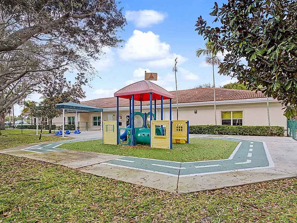 A playground with a small structure and a painted road on artificial grass