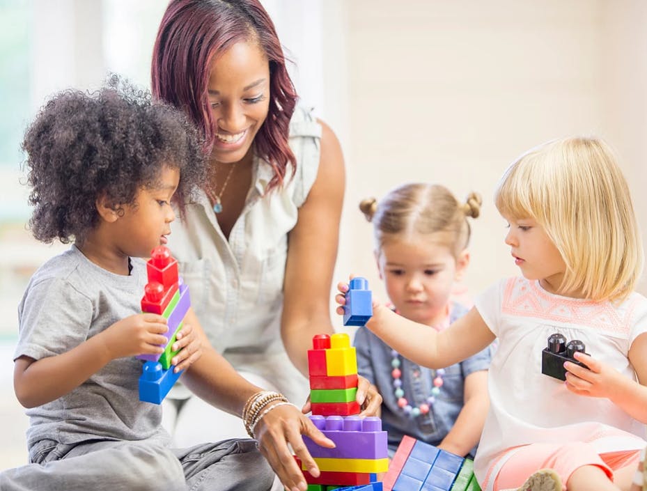 Adult and three children playing with colorful building blocks