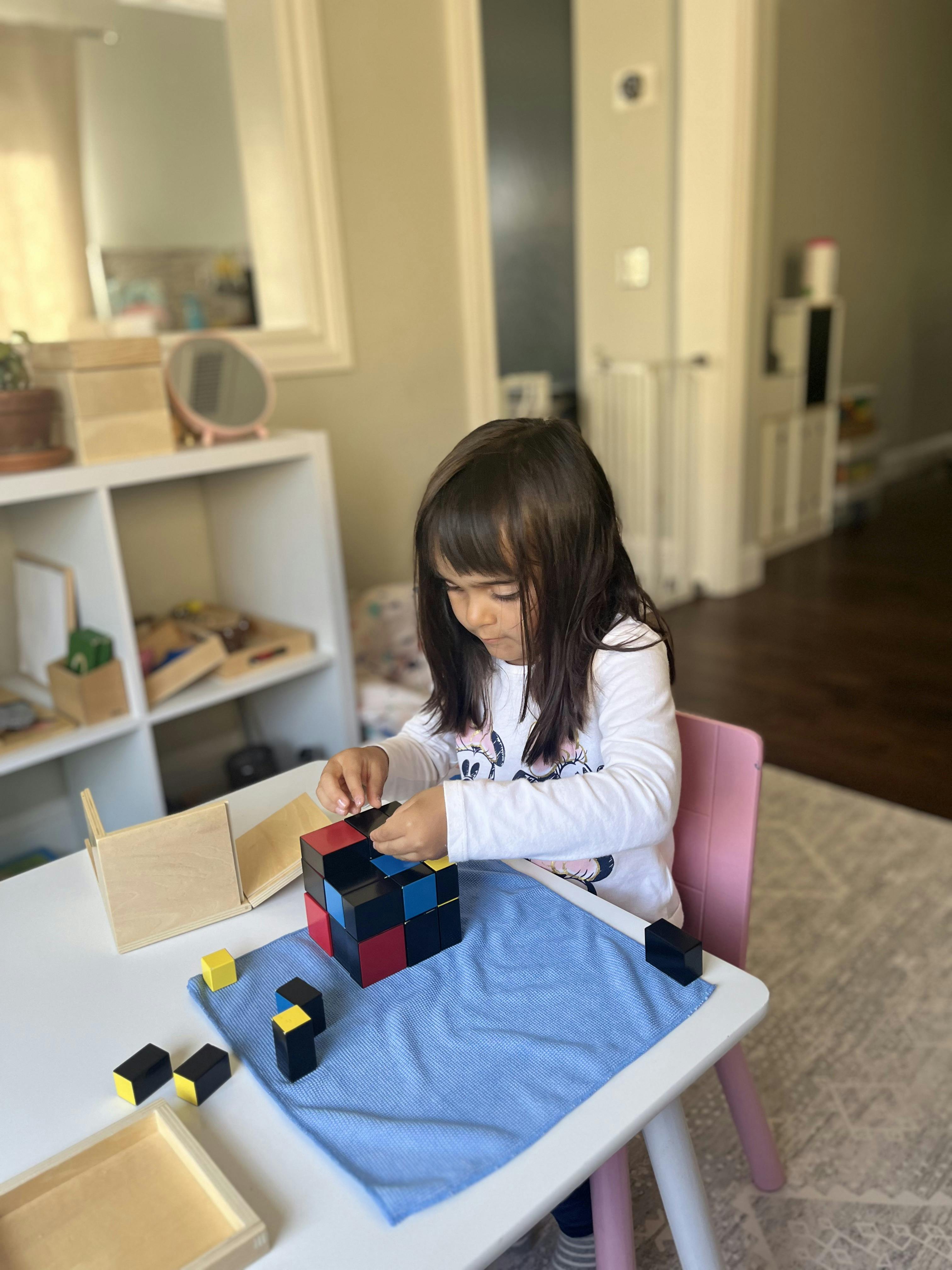 Child building with colorful blocks on a small white table