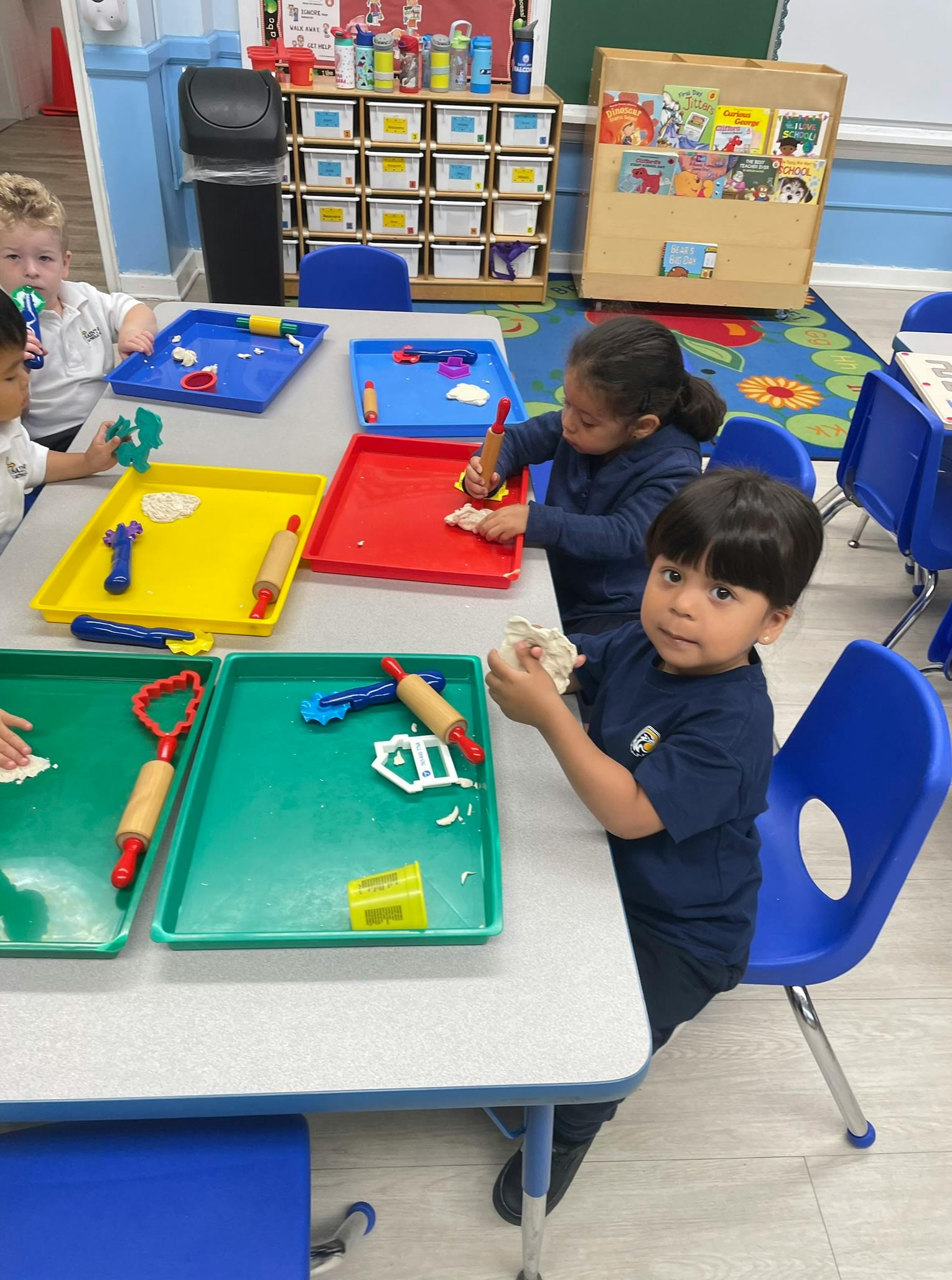 Children playing with modeling clay at a table in a classroom