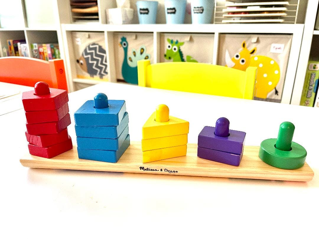 Wooden shape sorter toy with red, blue, yellow, purple, and green pieces