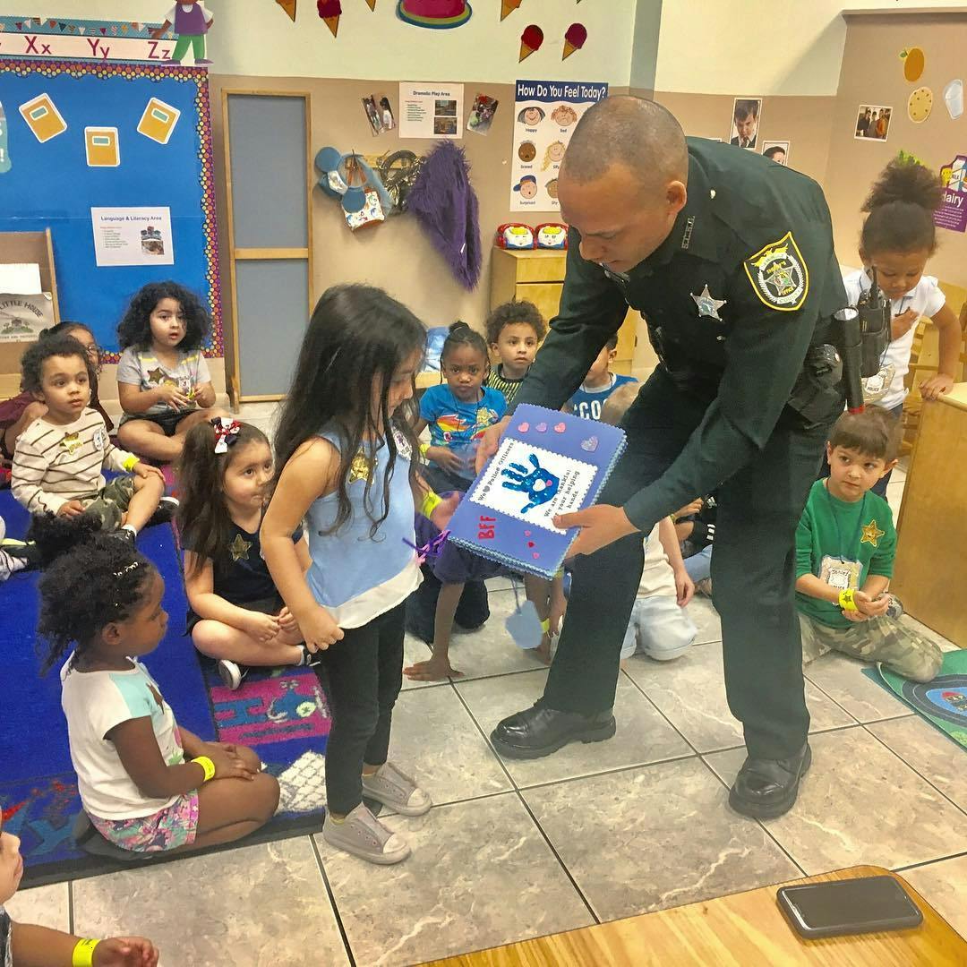 Person in uniform showing a book with a blue handprint to a child