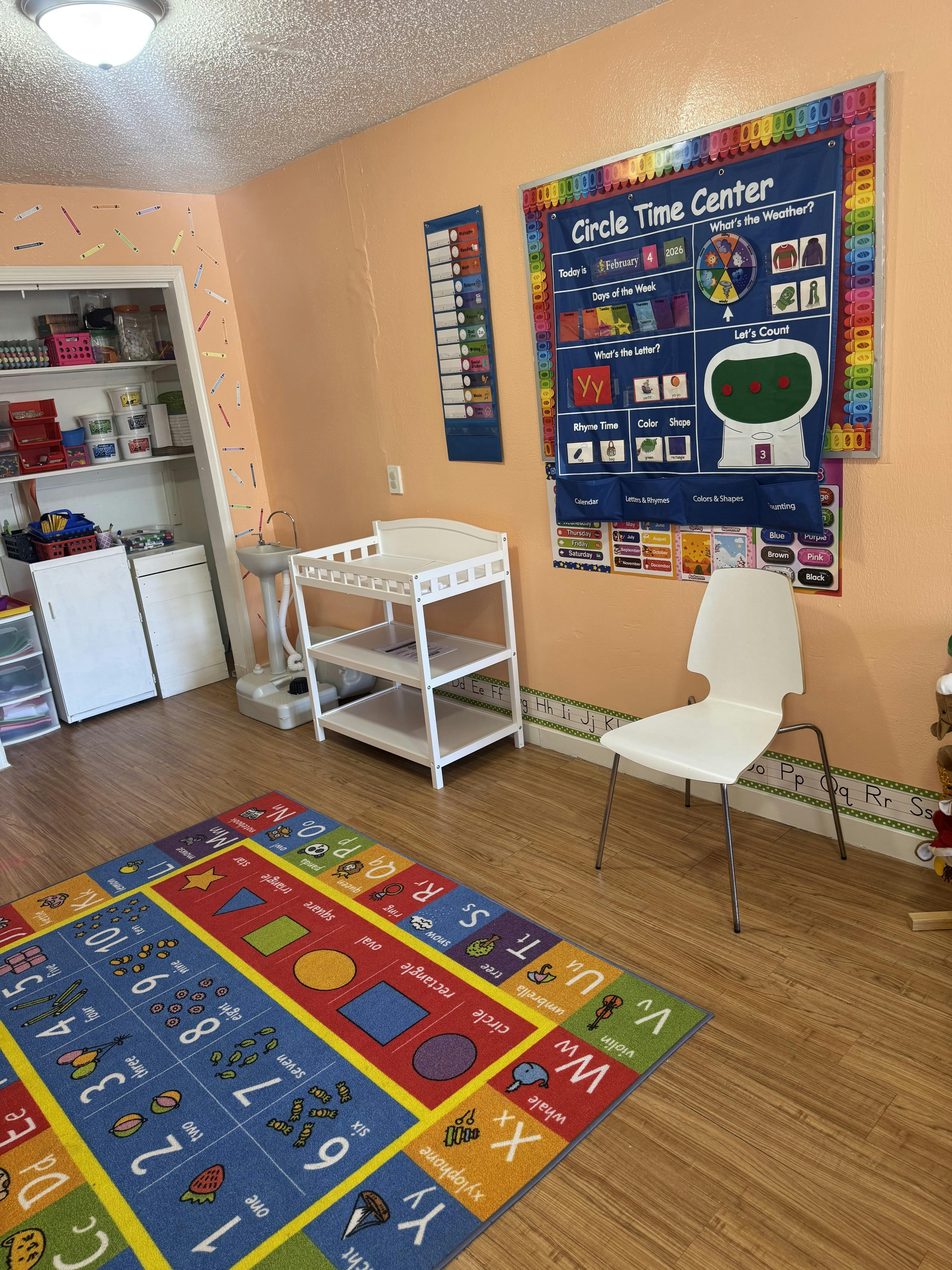 Classroom with a colorful alphabet and numbers rug, a Circle Time Center chart, and a changing table