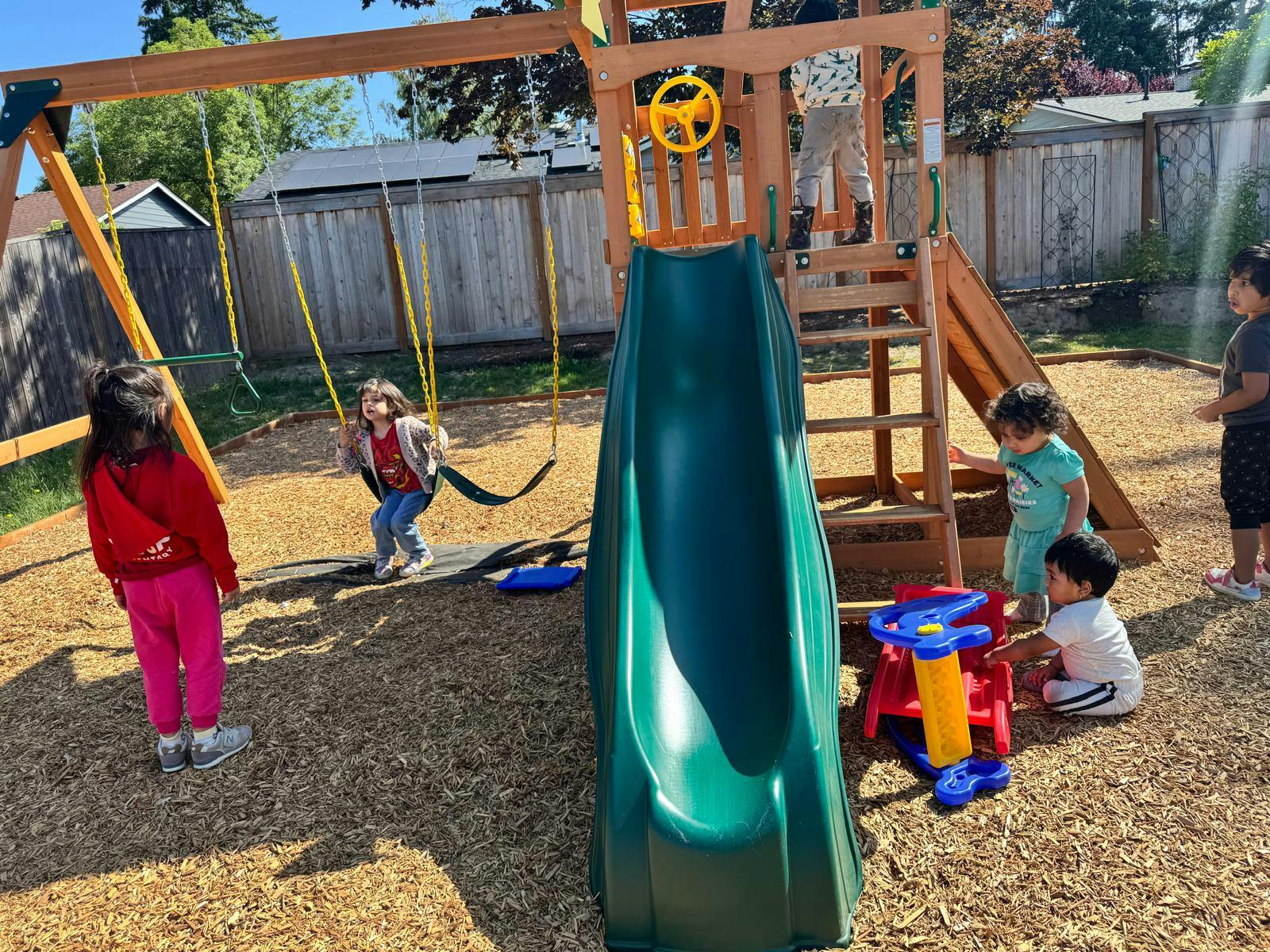 Children playing on a wooden playground with a slide and swings