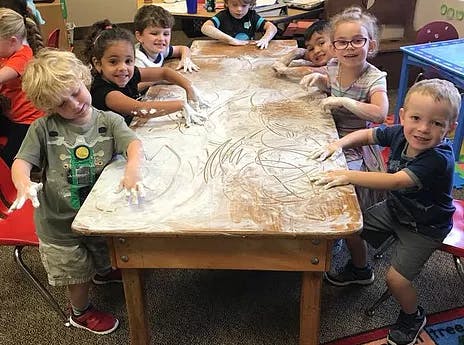 Children playing with flour on a table