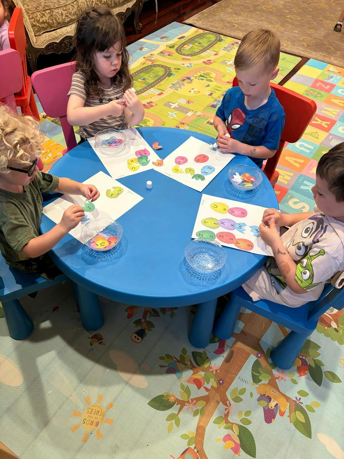 Four children doing a craft activity at a blue table