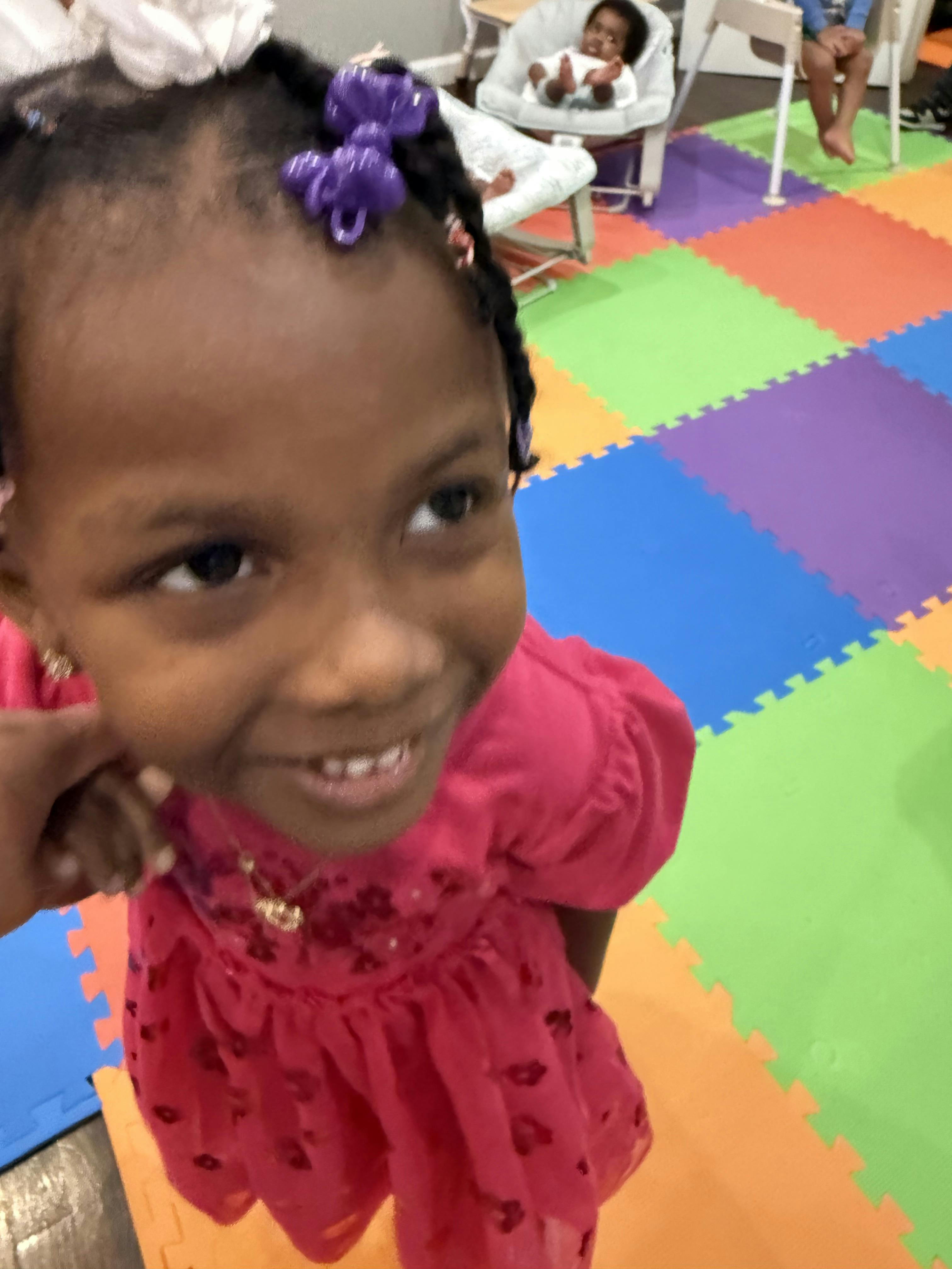 Child in a pink dress with purple hair ties