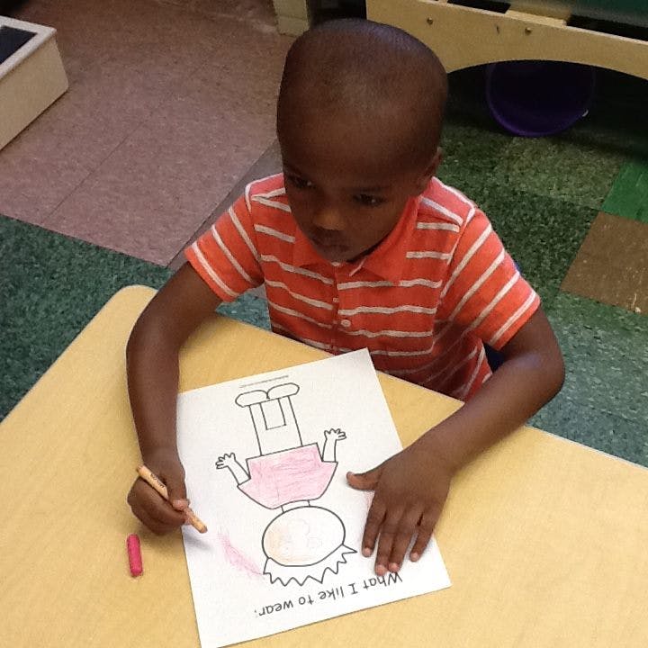 Child coloring a drawing of a person on a paper