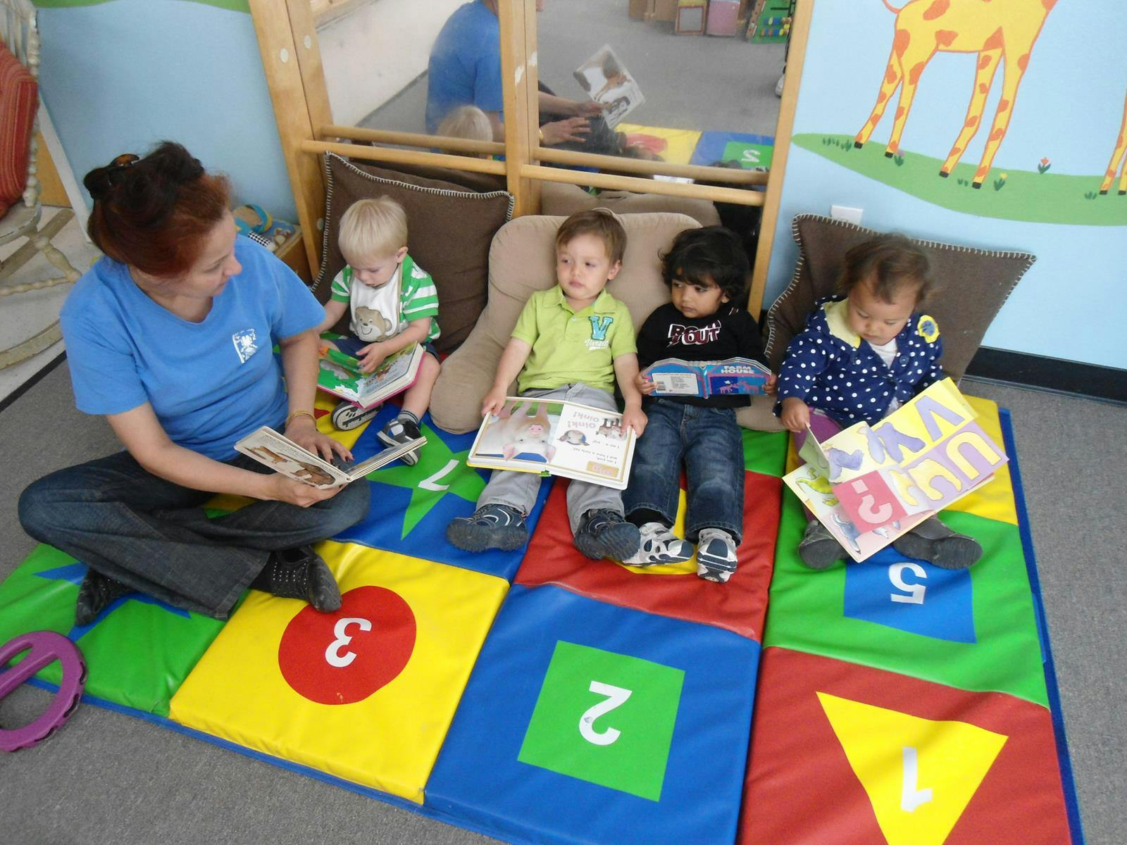 Person reading to four children in a classroom