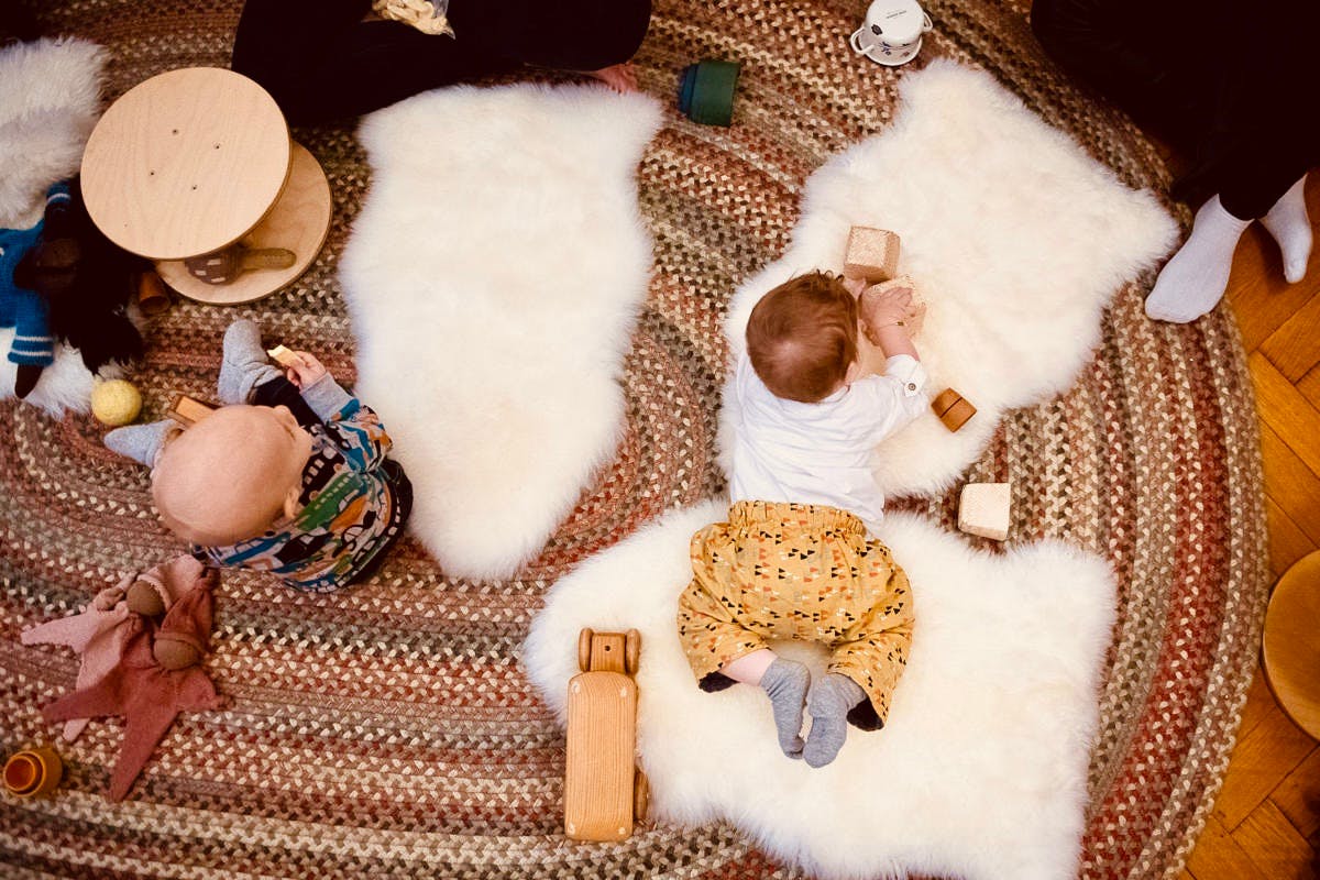 Two children playing on a rug with toys