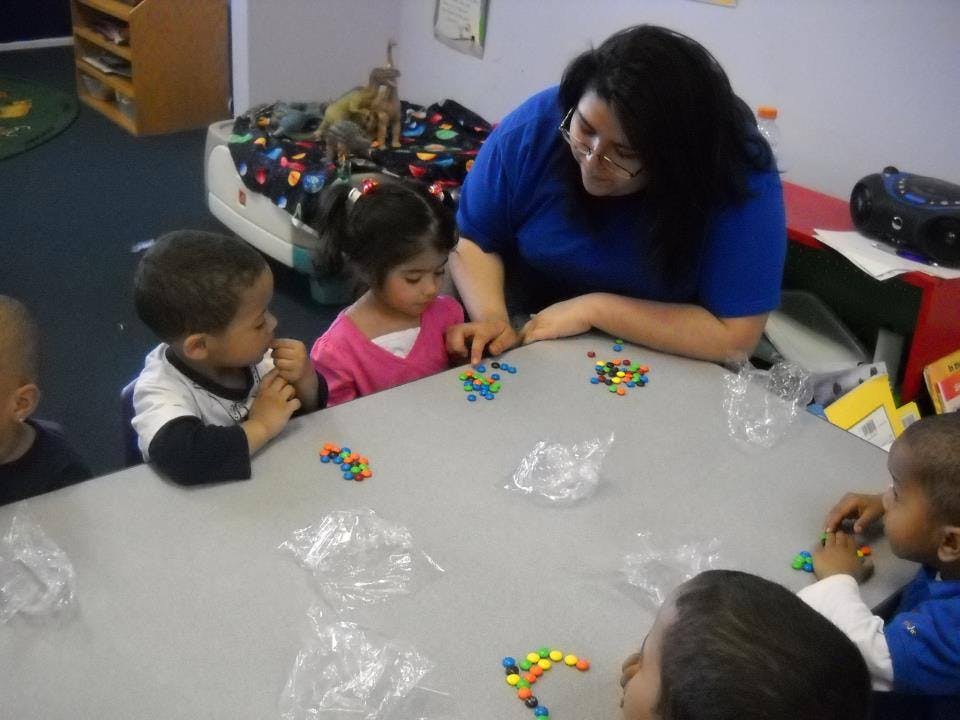 Adult and children at a table with colorful beads